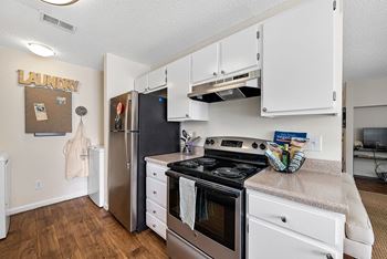 A kitchen with a stove, refrigerator, and cabinets.